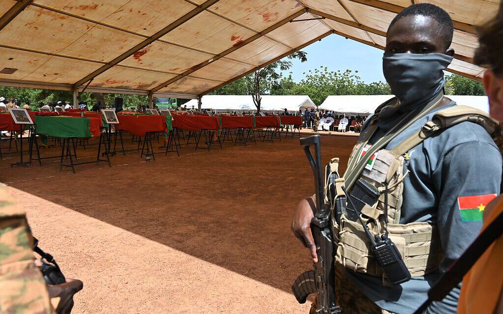 Un soldat monte la garde pendant les funérailles de 27 soldats tués alors qu'ils escortaient 207 véhicules dans un convoi à Gaskinde, lors d'une cérémonie au camp militaire Général Sangoule Lamizana à Ouagadougou le 8 octobre 2022.