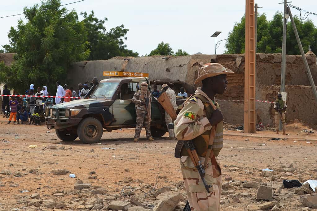 Des soldats maliens se tiennent à côté d'un bâtiment détruit le 13 novembre 2018 à Gao, après un attentat suicide à la voiture piégée qui a tué trois personnes. / AFP/