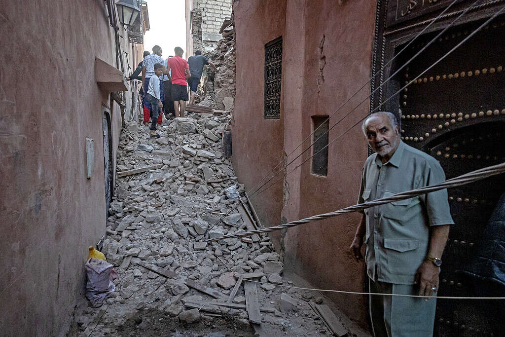 Un homme regarde des habitants naviguer dans les décombres de la vieille ville de Marrakech, endommagée par le tremblement de terre, le 9 septembre 2023. (Photo par FADEL SENNA / AFP)