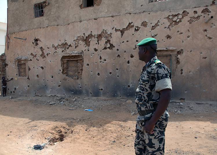 Le colonel Diarra, commandant de la défense de Gao, se tient près d'un bâtiment le 16 octobre 2013, montrant les cicatrices d'une attaque à la roquette le 7 octobre. AFP PHOTO/SEBASTIEN RIEUSSEC (Photo by Sebastien RIEUSSEC / AFP)