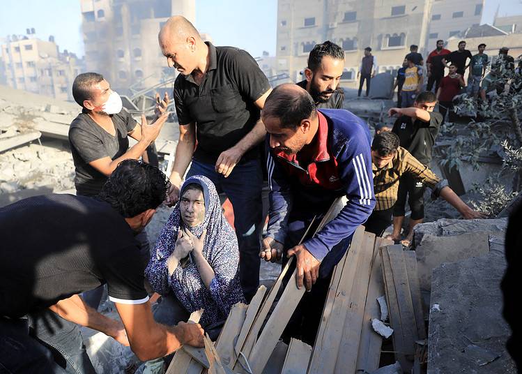 Une femme palestinienne est aidée, alors que des personnes cherchent des victimes sur le site d'une frappe israélienne sur un immeuble résidentiel dans la ville de Gaza, le 25 octobre 2023. REUTERS/Yasser Qudih