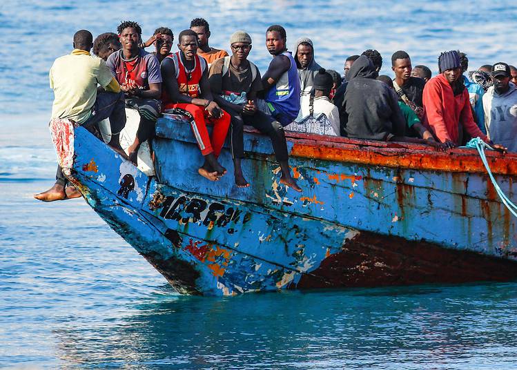 Des migrants attendent de débarquer d'un bateau remorqué par un navire des gardes-côtes.  14 octobre 2021. REUTERS/Borja Suarez.