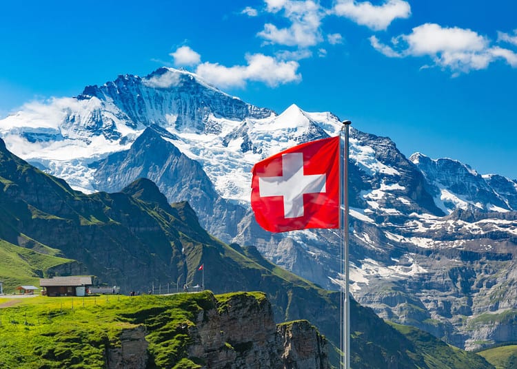 Drapeau suisse flottant et touristes admirant les sommets des montagnes Monch et Jungfrau sur le belvédère de Mannlichen, Oberland bernois, Suisse.