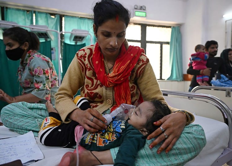 Une mère aide son enfant à respirer à l'aide d'un nébuliseur aux urgences. (Photo par Arun SANKAR / AFP)