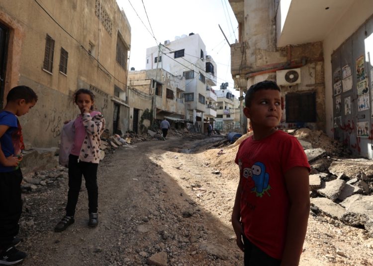 Des enfants palestiniens se tiennent sur une route détruite par un bulldozer de l'armée israélienne dans le camp de réfugiés de Jenin. (Photo by Zain JAAFAR / AFP)