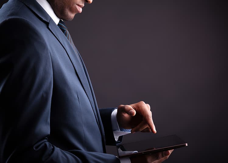 Businessman holding digital tablet on black background
