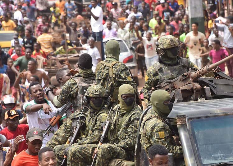 People celebrate in the streets with members of Guinea's armed forces after the arrest of Guinea's president, Alpha Conde, in a coup d'etat in Conakry, September 5, 2021. - Guinean special forces seized power in a coup on September 5, arresting the president and imposing an indefinite curfew in the poor west African country.
"We have decided, after having taken the president, to dissolve the constitution," said a uniformed officer flanked by soldiers toting assault rifles in a video sent to AFP. (Photo by CELLOU BINANI / AFP)
