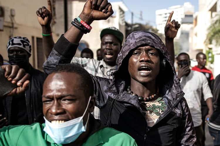 TOPSHOT - Protesters gesture after police fired teargas at them outside the General Assembly in Plateau, Dakar on February 5, 2024. Security forces used tear gas to disperse an opposition rally outside Senegal's parliament on February 5, 2024, shortly before the start of a contentious debate on postponing this month's presidential election. (Photo by JOHN WESSELS / AFP)