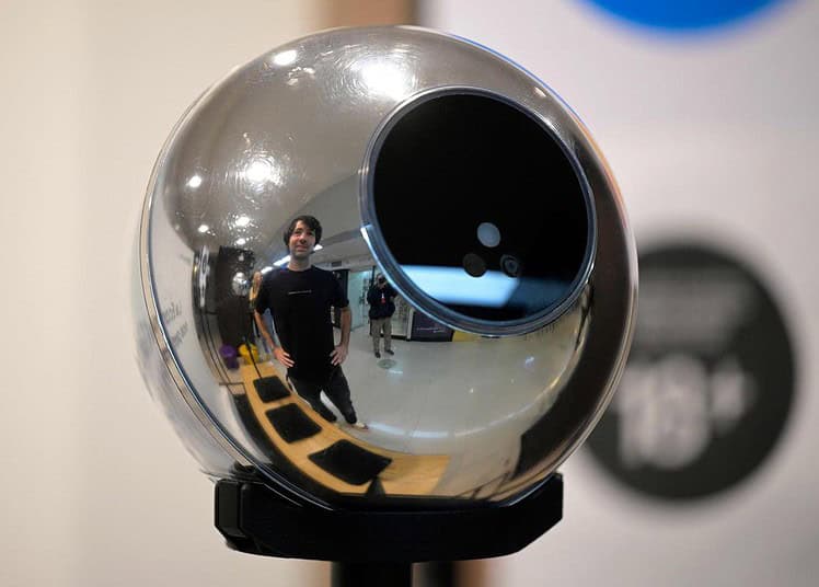 Martin Mazza, regional manager of Tools for Humanity, poses reflected on an orb, a biometric data scanning device used to scan the iris of people in exchange for the cryptocurrency Worldcoin, in Buenos Aires on March 22, 2024. In recent months, hundreds of thousands of Argentines have stood in front of a Worldcoin orb to scan the iris of their eyes in inflation-hit Argentina, where recent tightening delivered the coup de grace. The Worldcoin cryptocurrency, with a verification system based on iris recognition and launched in July 2023 by OpenAI CEO Sam Altman, is being closely watched by regulators in several countries due to data protection concerns. (Photo by JUAN MABROMATA / AFP)