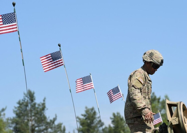 (FILES) This file photo taken on May 11, 2016 shows a US soldier standing next to US flags the military training area in Grafenwoehr, near Eschenbach, southern Germany, during the exercise "Strong Europe Tank Challenge 2016". - The United States will station 500 more military personnel in Germany in a bid to strengthen bilateral ties, Defense Secretary Lloyd Austin said on April 13, 2021 at the start of his first visit to Europe. (Photo by CHRISTOF STACHE / AFP)