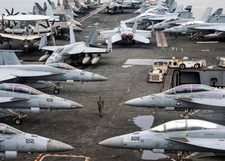 (FILES) A US Navy officer walks past fighter jets sitting on the flight deck of the Nimitz-class aircraft carrier USS Abraham Lincoln during a media tour in Port Klang, on the outskirts of Kuala Lumpur, on November 26, 2024. A US naval strike group led by the USS Abraham Lincoln aircraft carrier has deployed to Middle Eastern waters, the United States said on January 26, 2026, as Tehran warned it was ready to hit back at any American attack launched in response to a crackdown on anti-government protests. (Photo by FAZRY ISMAIL / POOL / AFP)