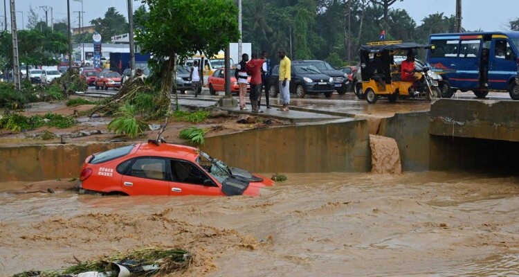 A taxi is swept away by torrential rain in Bingerville near Abidjan on June 21, 2022. (Photo by Issouf SANOGO / AFP)