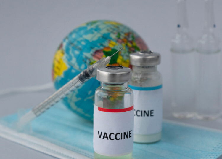 vaccine in two ampoules with syringe near , toy globe and three transparent ampoules with medicine on medical mask, universal vaccination to save world. Copy space; Shutterstock ID 1913323726; purchase_order: Doctissimo; job: Digital